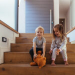 Kleine Kinder sitzen auf einer Treppe und der Junge greift nach einem Teddybär.